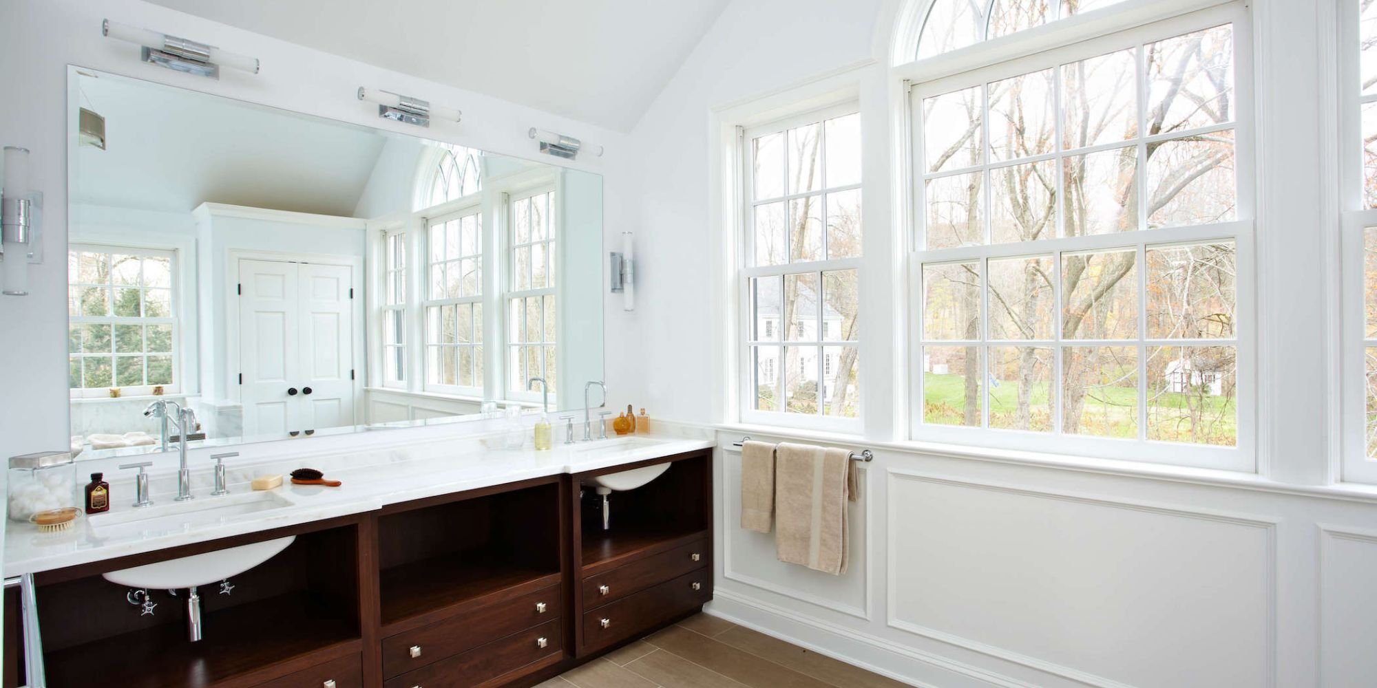 A Greenwich, CT bathroom remodel with large windows spanning one wall adjacent to a double custom vanity by TR Design-Build