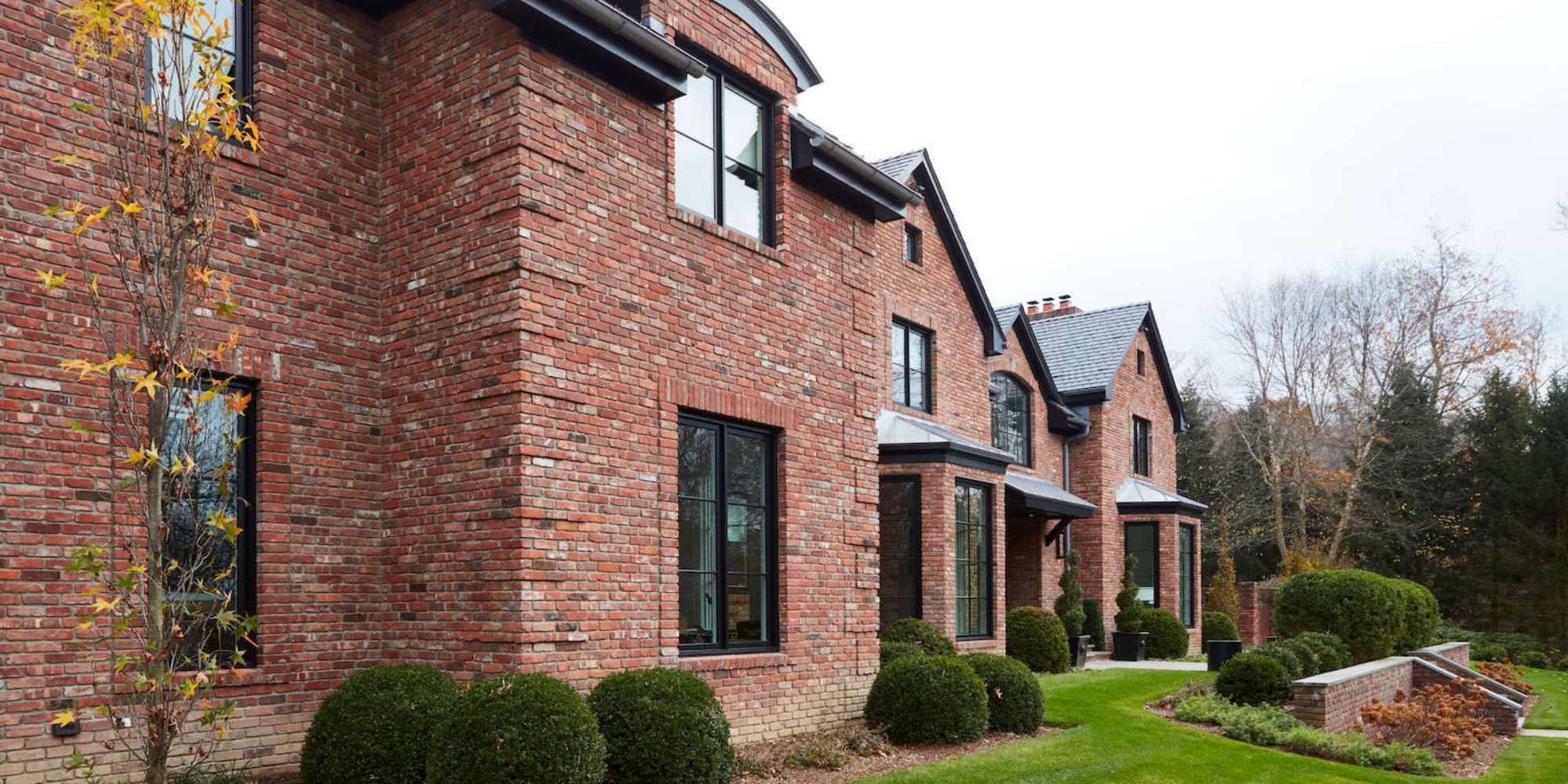Brick custom home in New Canaan with black window frames and manicured lawn by TR Design Build