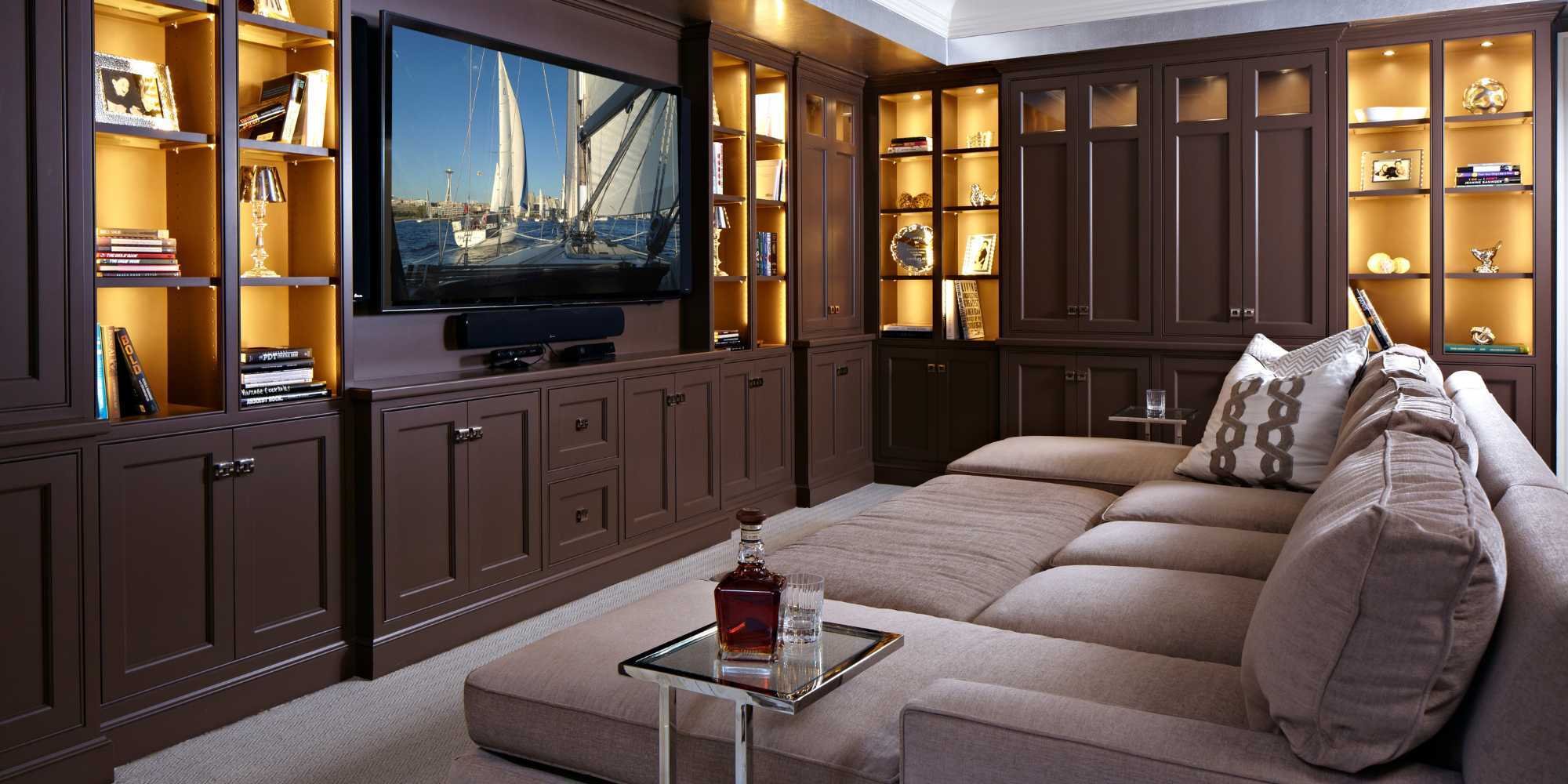 Cozy home theater with custom built-in cabinetry, warm accent lighting, and a plush sectional by TR Design Build in New Canaan, CT