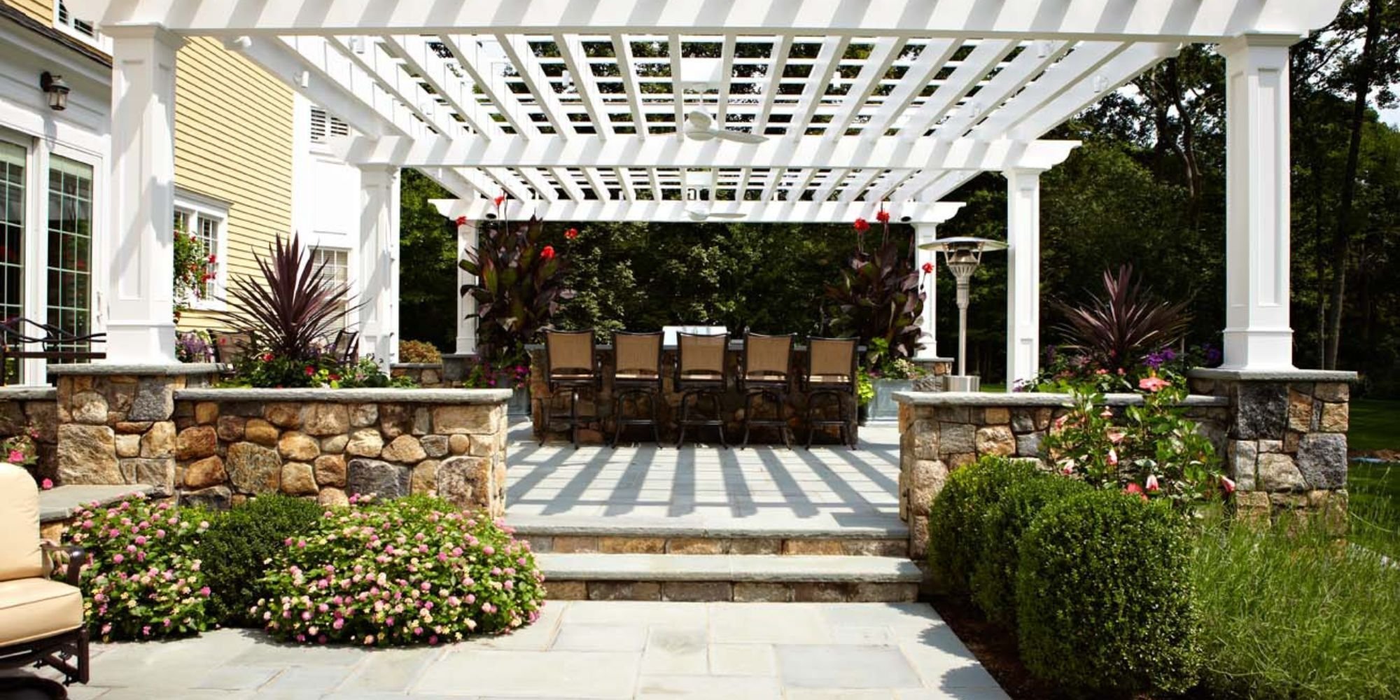 Elegant outdoor living space in New Canaan with pergola and stonework by TR Design Build
