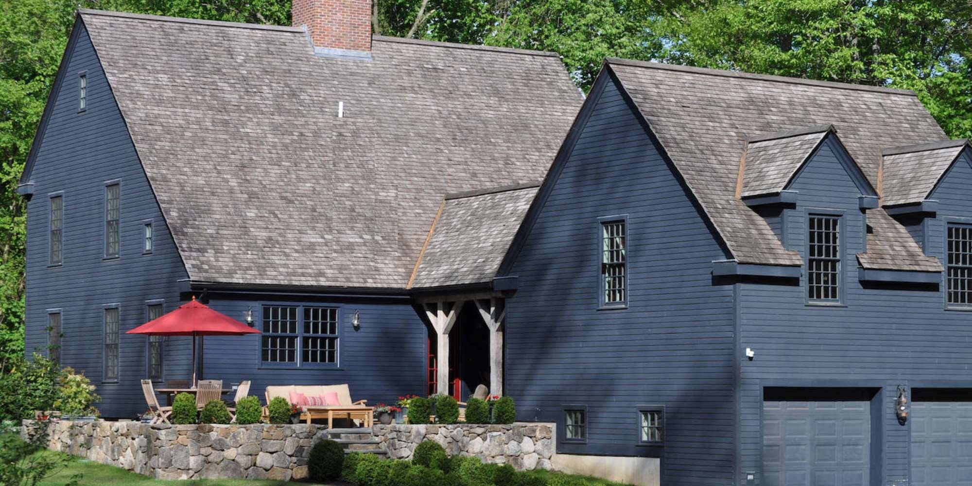Whole home remodel with navy siding and stone patio by TR Design Build in New Canaan, CT
