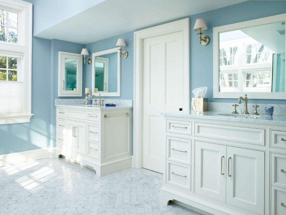 Custom bathroom with dual vanities, stone countertops, and blue walls by TR Design-Build
