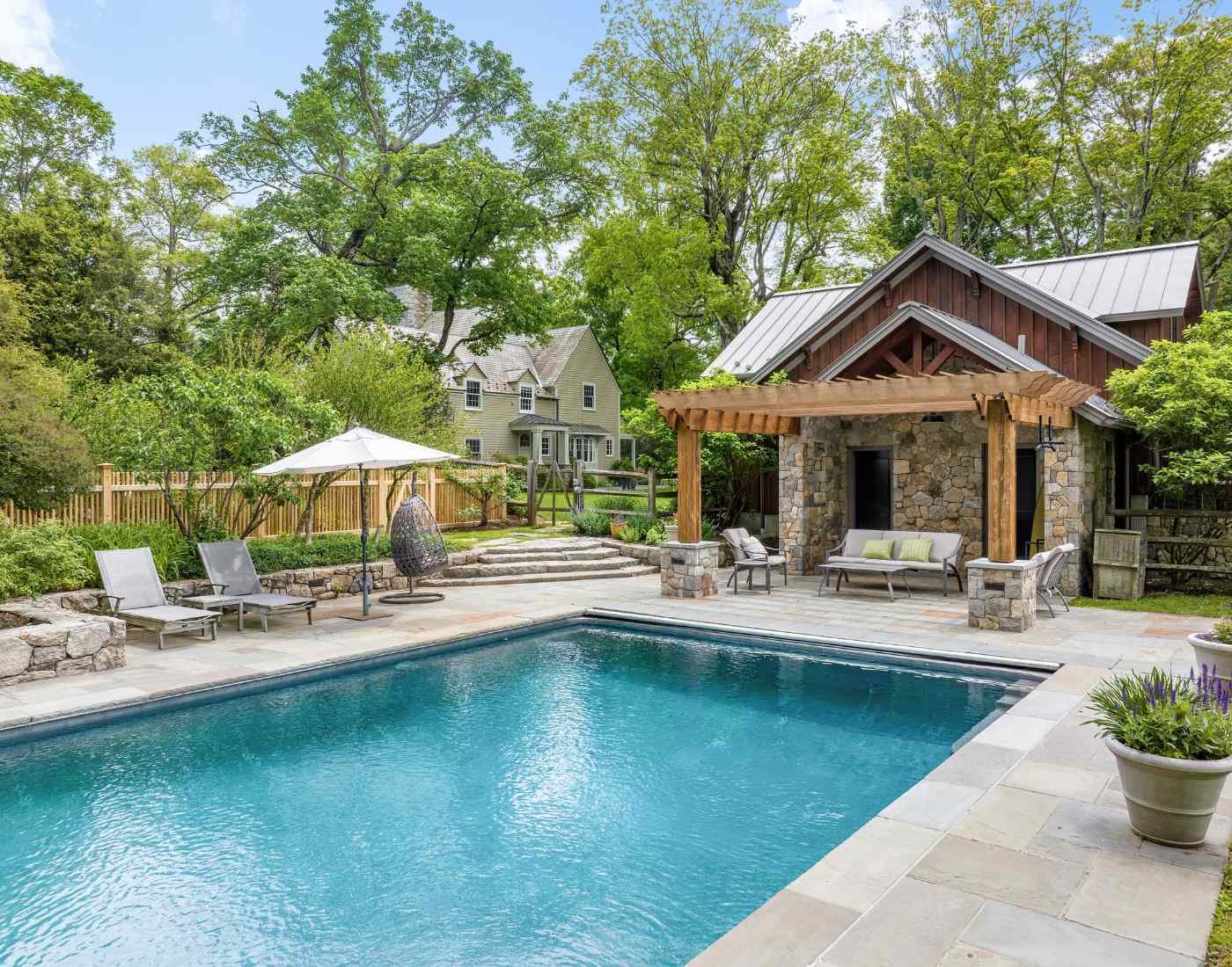 An accessory structure with wood pergola and stone features by TR Design Build in New Canaan, CT