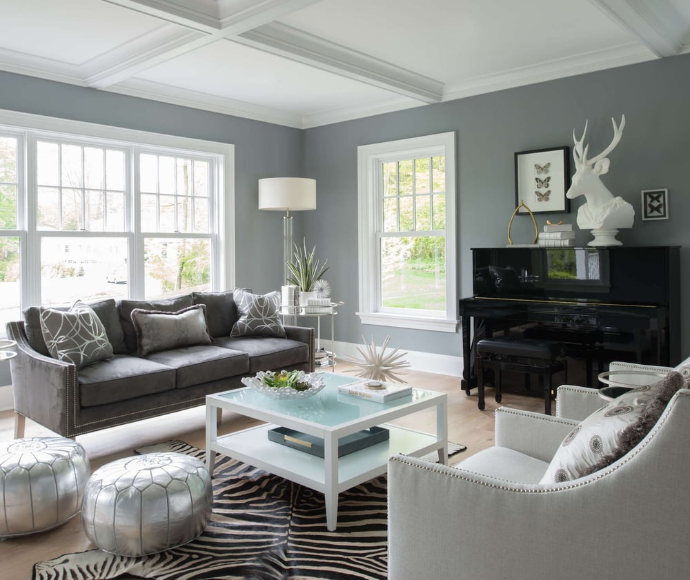 A remodeled living room with lots of natural light, grey walls with white trim, and hardwood floors.