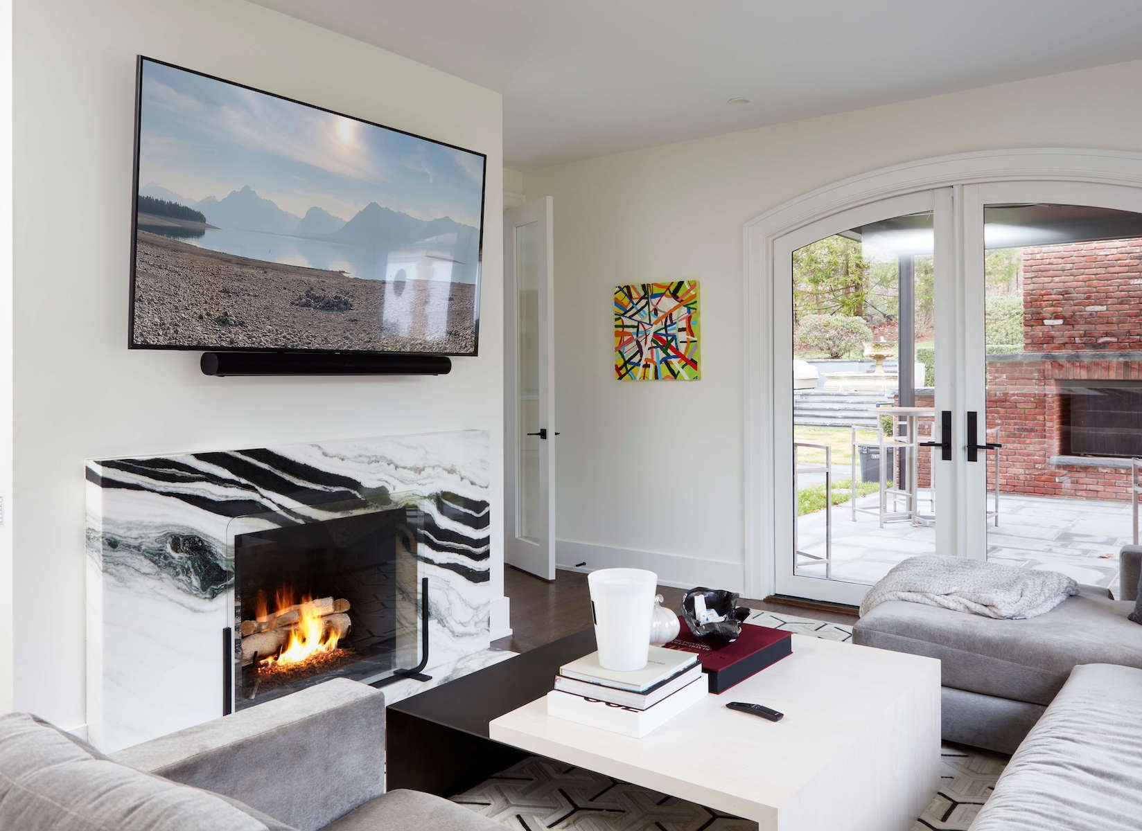 A custom renovated living room with a marble fireplace and french doors by TR Design-Build