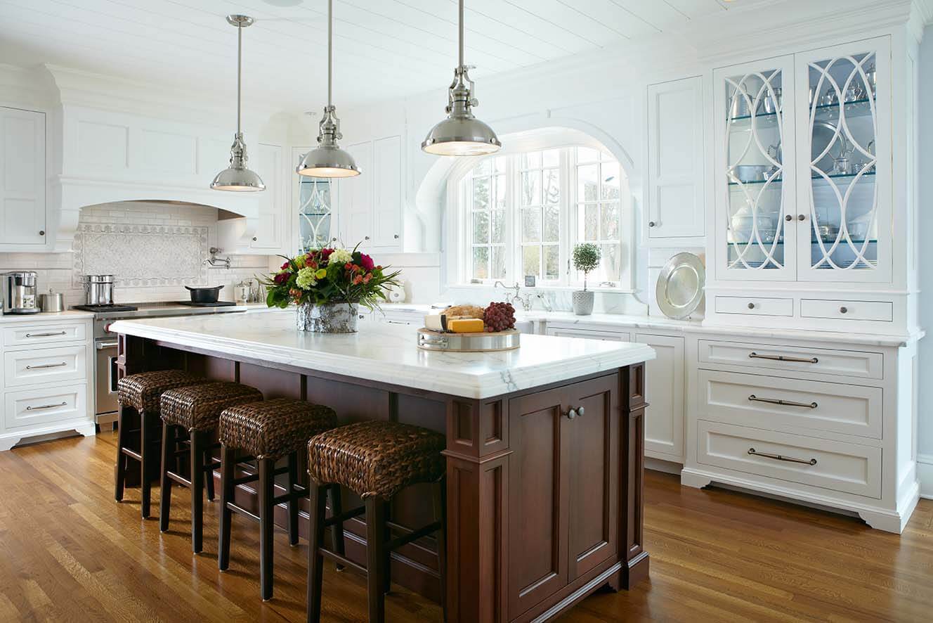 A remodeled kitchen featuring custom built-in storage, pendant lighting, marble countertops, and a large island with seating by TR Design-Build