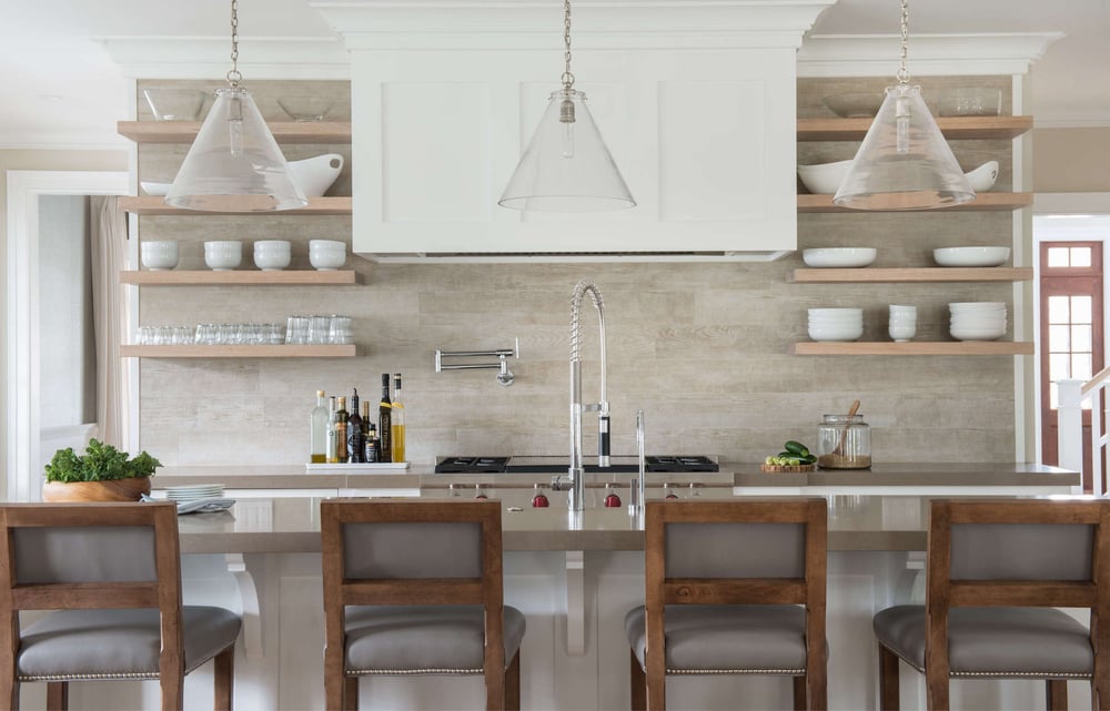 Custom remodeled Connecticut kitchen featuring a large island with a sink, seating, and pendant lighting, floating shelves on the walls, and a large hood fan above the stove, by TR Design-Build