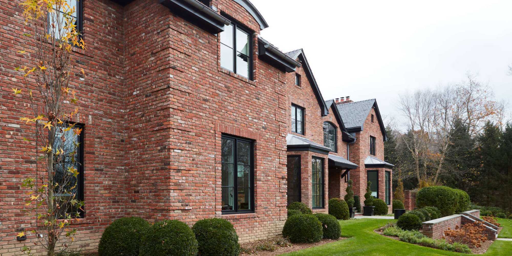 Brick custom home in New Canaan with black window frames and manicured lawn by TR Design Build