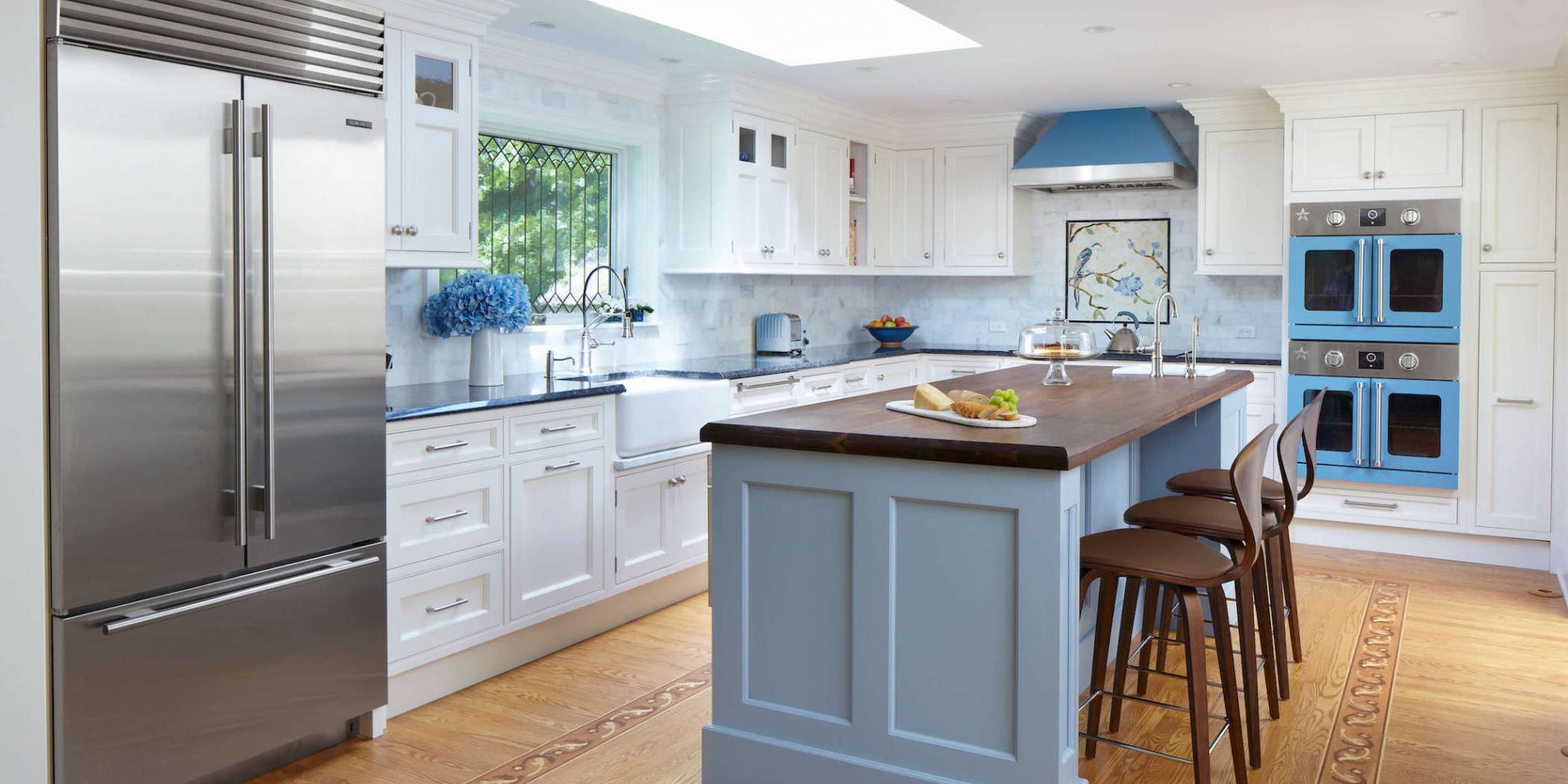 Kitchen remodel with a skylight, large island with seating, and blue accents by TR Design-Build in New Canaan, CT