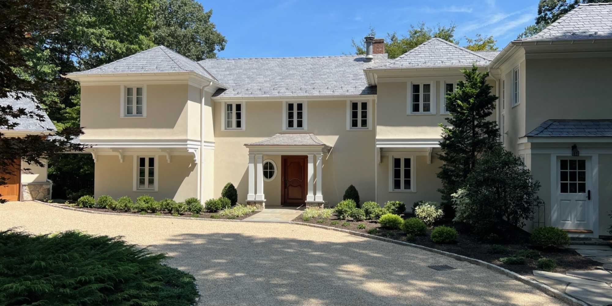 Custom home in New Canaan, CT by TR Design Build with stucco exterior, gravel driveway, and formal front entry