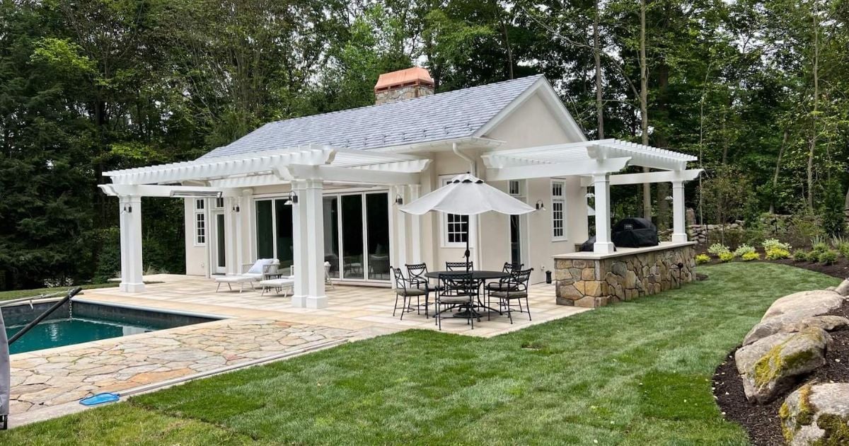 Pool house with pergola and stone patio by TR Design Build in New Canaan, CT