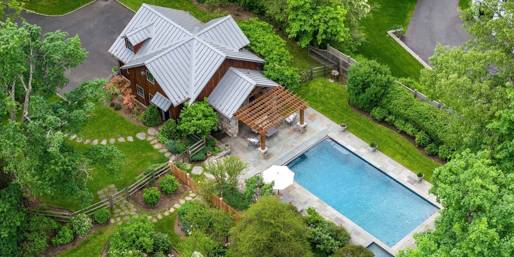 Aerial view of a barn-inspired detached garage accessory structure connected to a pool area by TR Design-Build in New Canaan, CT.