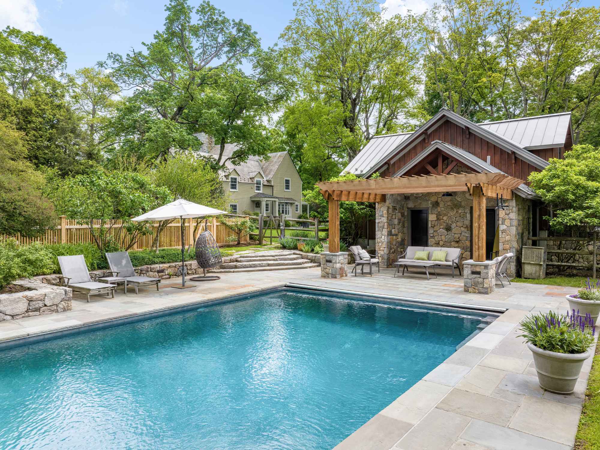 Detached garage connected to a pool area with a stone facade and wooden pergola in New Canaan, CT by TR Design-Build Detached garage connected to a pool area with a stone facade and wooden pergola in New Canaan, CT by TR Design-Build